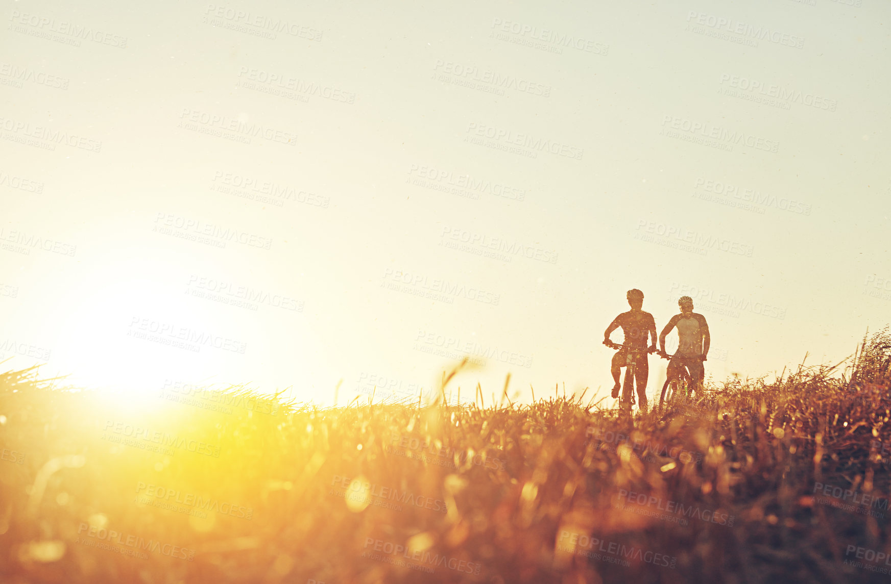 Buy stock photo Sunset sky, people and friends on bicycle with grass, race and adventure trail in nature together. Cycling, fitness and team with mountain bike in evening for outdoor workout, sun and fun exercise