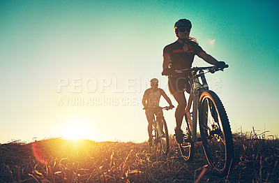 Buy stock photo Sunset, people and friends on bicycle with adventure, race and exercise trail in nature together. Cycling, fitness and team with mountain bike in evening for outdoor workout, blue sky and grass path