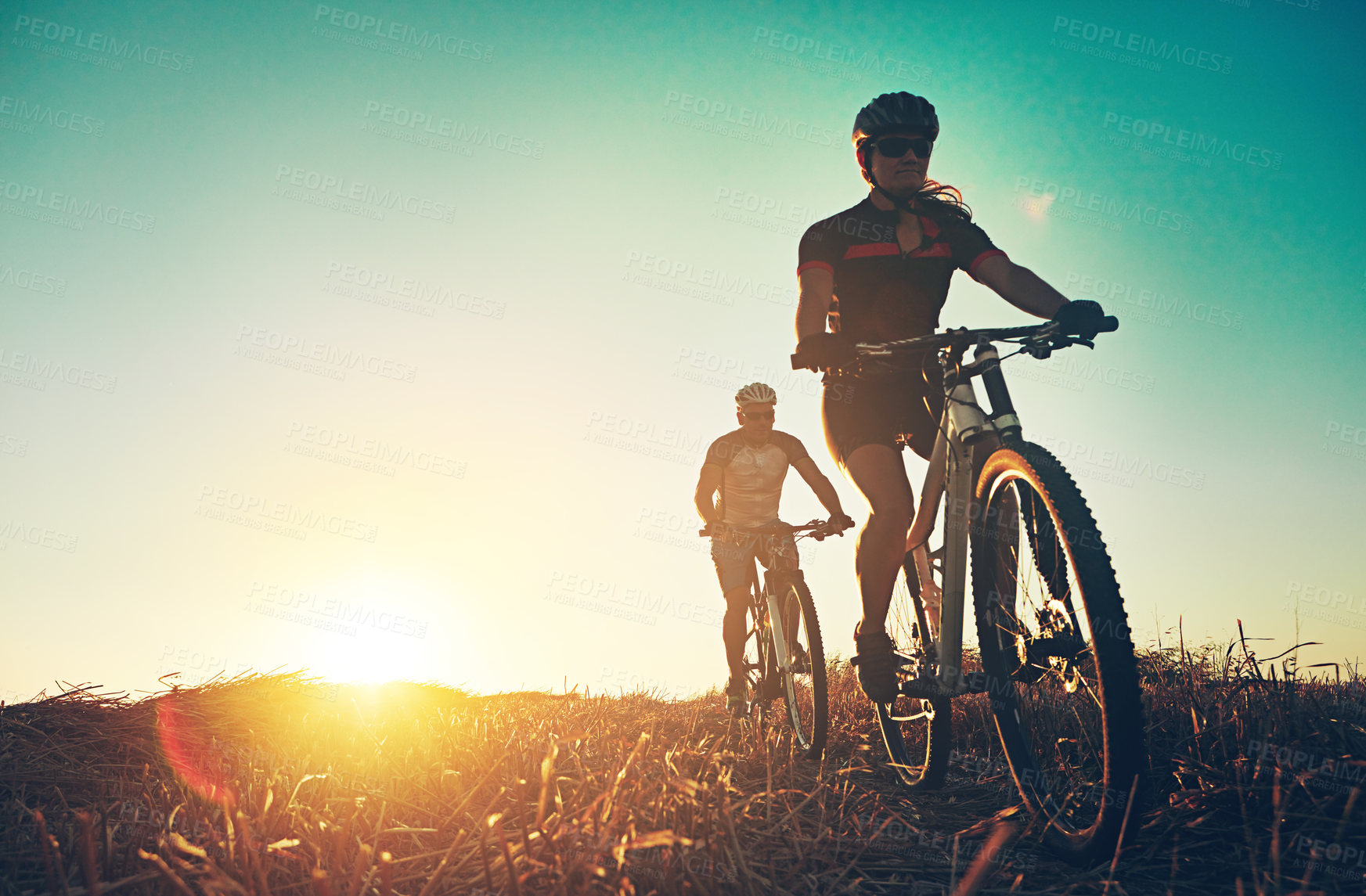 Buy stock photo Sunset, people and friends on bicycle with adventure, race and exercise trail in nature together. Cycling, fitness and team with mountain bike in evening for outdoor workout, blue sky and grass path