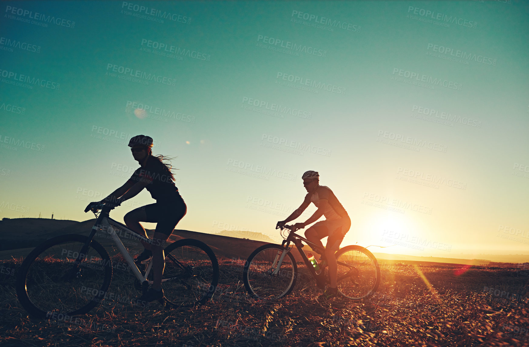 Buy stock photo Sunset, silhouette and people on bicycle with fitness, race and exercise in nature together. Cycling, adventure and friends with mountain bike in evening for outdoor workout, blue sky and grass path