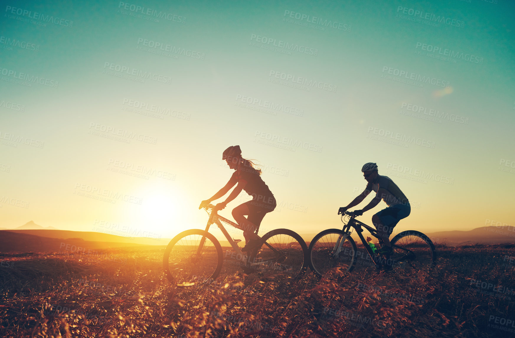 Buy stock photo Sunset, silhouette and people on bicycle with adventure, race and exercise in nature together. Cycling, fitness and friends with mountain bike in evening for outdoor workout, blue sky and grass path