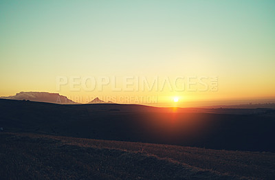 Buy stock photo Shot of the sun setting over a beautiful rural landscape