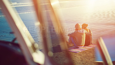 Buy stock photo Rearview shot of a young couple sitting on the beach