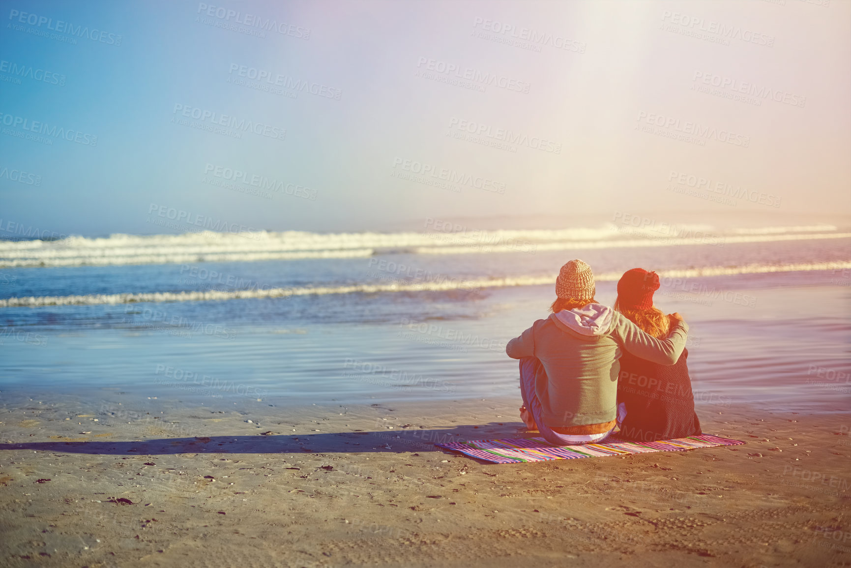 Buy stock photo Rearview shot of a young couple sitting on the beach