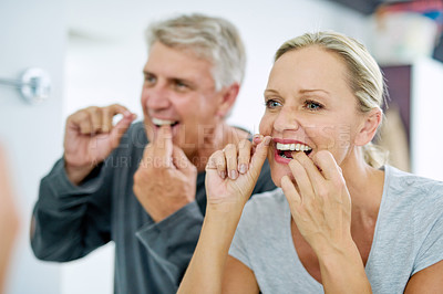 Buy stock photo Senior, couple and floss their teeth for fresh breath and a smile and healthcare at home. Elderly woman and man  cleaning mouth for dental care in the bathroom for a healthy lifestyle and insurance.