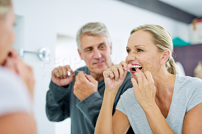 Buy stock photo Senior woman, man and floss for dental in the bathroom for fresh breath in the morning with results. Elderly, couple and clean their teeth for healthy smile with mirror for hygiene care at home.