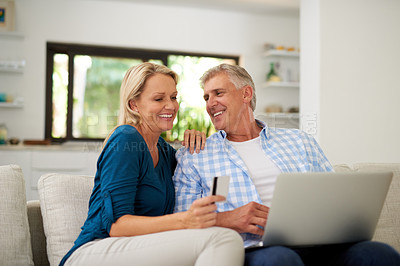 Buy stock photo Cropped shot of a mature couple making a credit card payment on a laptop at home