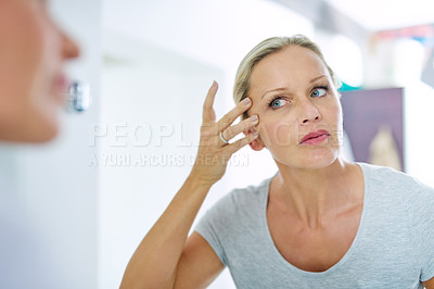Buy stock photo Cropped shot of a mature woman inspecting her skin in front of the bathroom mirror