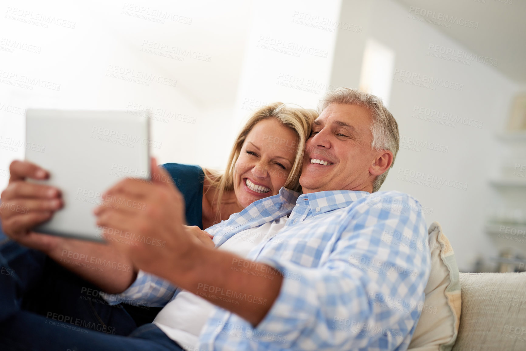 Buy stock photo Cropped shot of a mature couple taking a selfie on a digital tablet at home