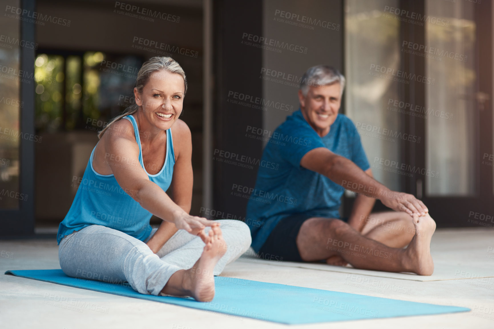 Buy stock photo Shot of a mature and happy couple stretching before they do yoga outside of their home