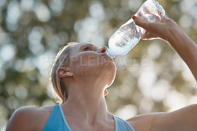 Buy stock photo Shot of mature and fit woman having a drink from a water bottle in the outdoors