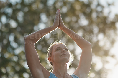 Buy stock photo Shot of mature and fit woman engaging in a standing yoga pose with her hands touching above her head