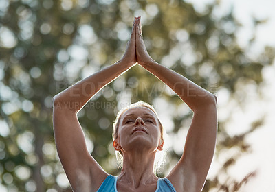 Buy stock photo Shot of mature and fit woman engaging in a standing yoga pose with her hands touching above her head