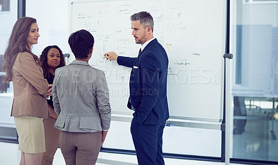 Buy stock photo Cropped shot of a group of businesspeople working on a whiteboard in the boardroom