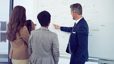 Buy stock photo Rearview shot of a group of businesspeople working on a whiteboard in the boardroom