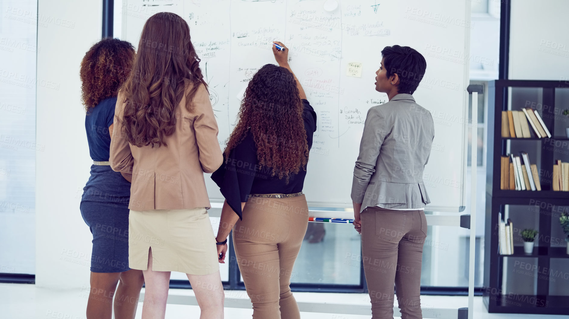 Buy stock photo Rearview shot of a group of businesswomen working on a whiteboard in the boardroom