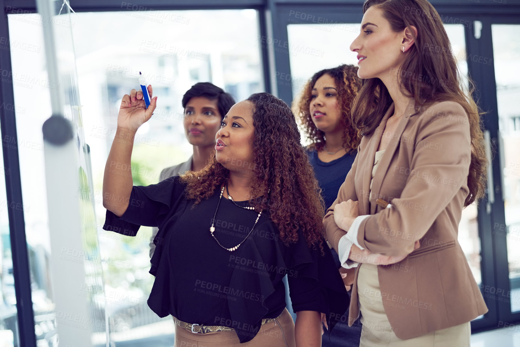 Buy stock photo Cropped shot of a group of businesswomen working on a whiteboard in the boardroom