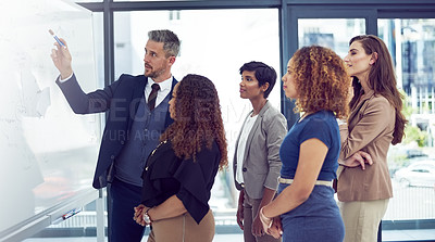 Buy stock photo Cropped shot of a group of businesspeople working on a whiteboard in the boardroom