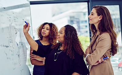 Buy stock photo Cropped shot of a group of businesswomen working on a whiteboard in the boardroom