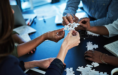 Buy stock photo Cropped shot of a group of unidentifiable colleagues building a puzzle together at a table in the boardroom
