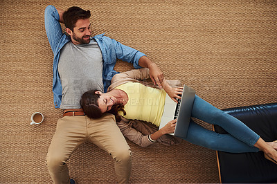 Buy stock photo High angle shot of an affectionate young couple relaxing on their living room floor