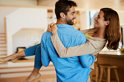 Buy stock photo Rearview shot of a young man carrying his beautiful wife through their home