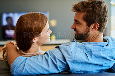 Buy stock photo Rearview shot of an affectionate young couple relaxing on the sofa at home