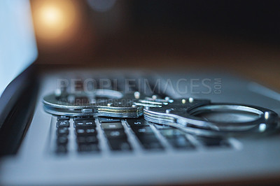 Buy stock photo Shot of a pair of handcuffs lying on a laptop keyboard in the dark