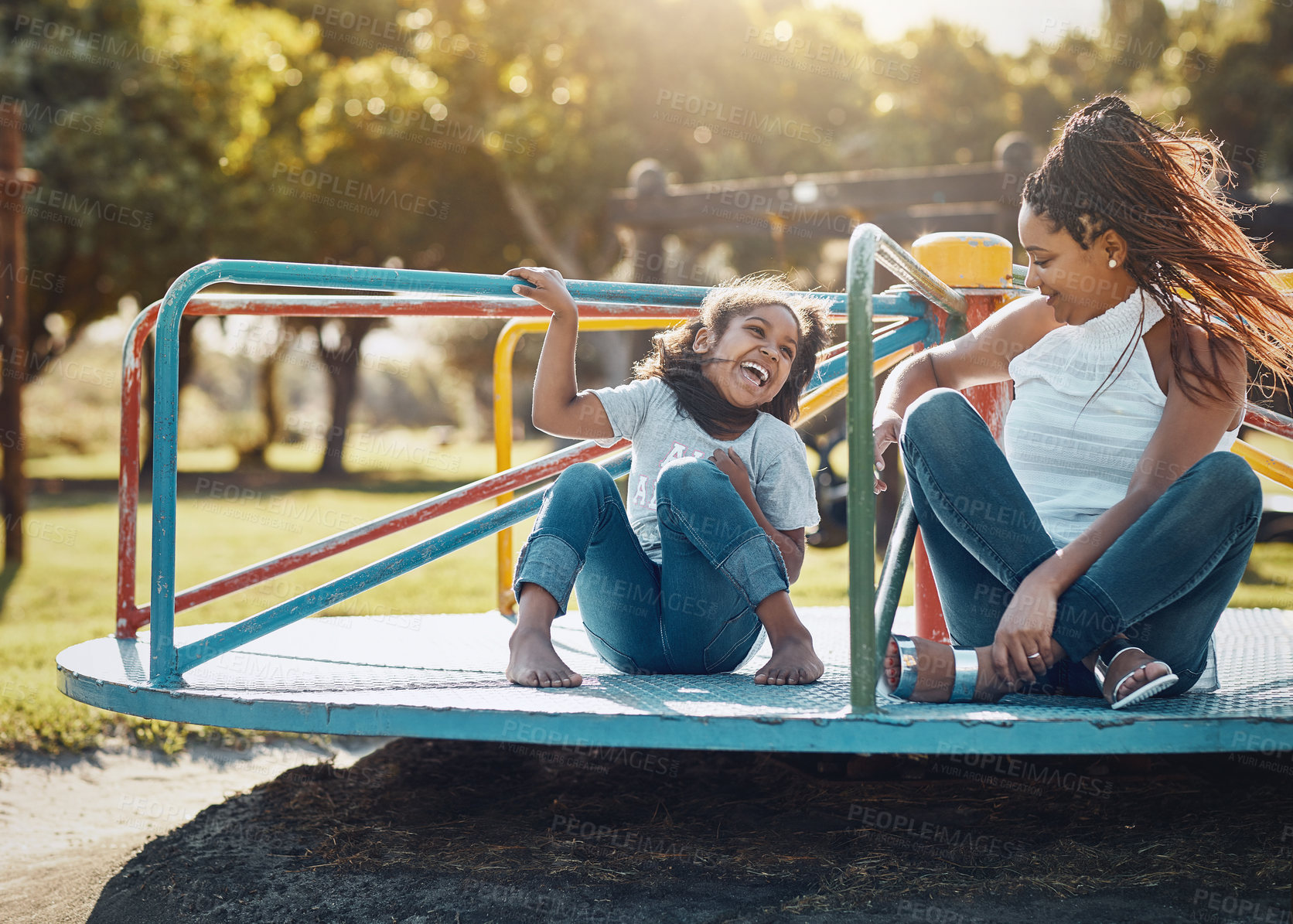 Buy stock photo Mother with daughter on roundabout at park, playing together with laughter and fun outdoor. Love, care and bonding with family happiness, woman and girl enjoying time at playground with freedom