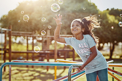 Buy stock photo Cropped shot of an adorable little girl playing with bubbles at the park