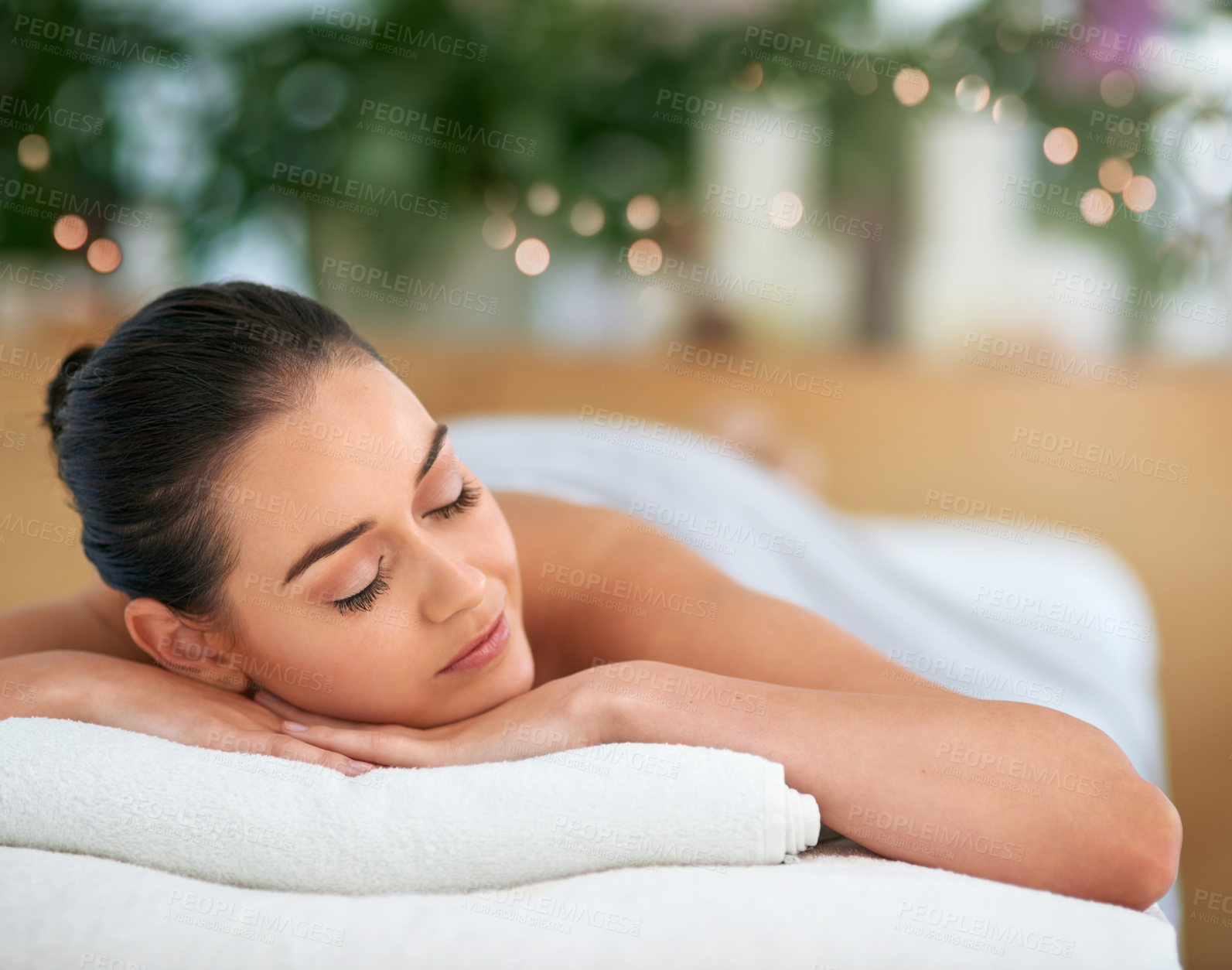 Buy stock photo Cropped shot of an attractive young woman relaxing on a massage table at a spa