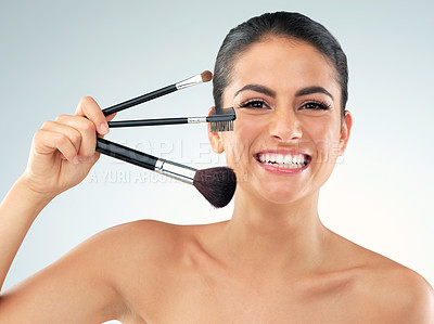 Buy stock photo Studio shot of a beautiful young woman holding makeup brushes against a gray background