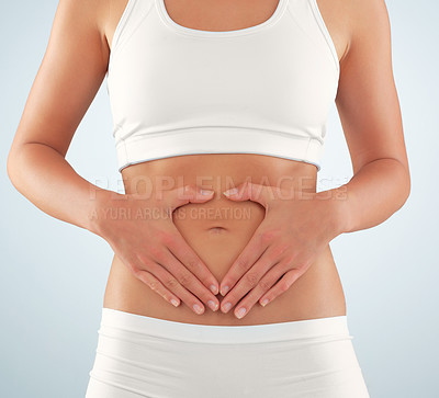 Buy stock photo Cropped studio shot of a fit young woman with her hands framing her stomach against a gray background