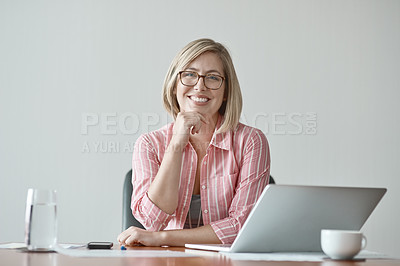Buy stock photo Studio portrait of a confident businesswoman sitting at a desk against a grey background
