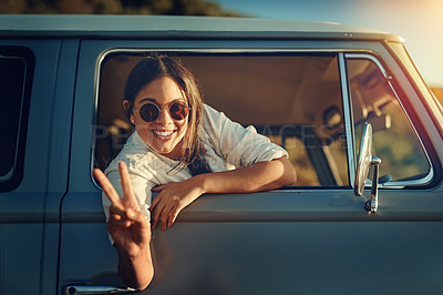 Buy stock photo Shot of a young woman leaning out of a van’s window and showing a peace sign on a roadtrip