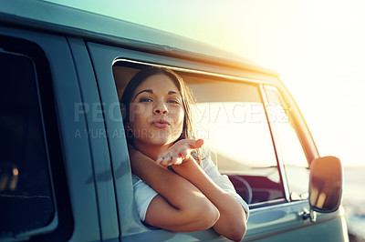 Buy stock photo Shot of a young woman leaning out of a van’s window and blowing a kiss on a roadtrip