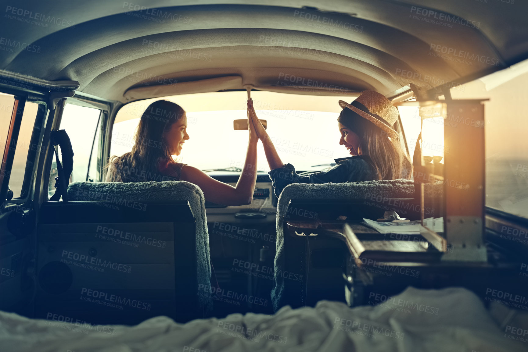 Buy stock photo Shot of two young friends giving each other a highfive on a road trip