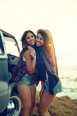 Buy stock photo Shot of two affectionate friends stopping at the beach during their roadtrip
