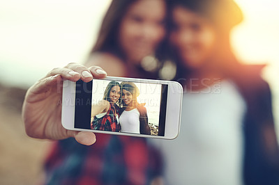 Buy stock photo Shot of two young friends taking a selfie together outdoors