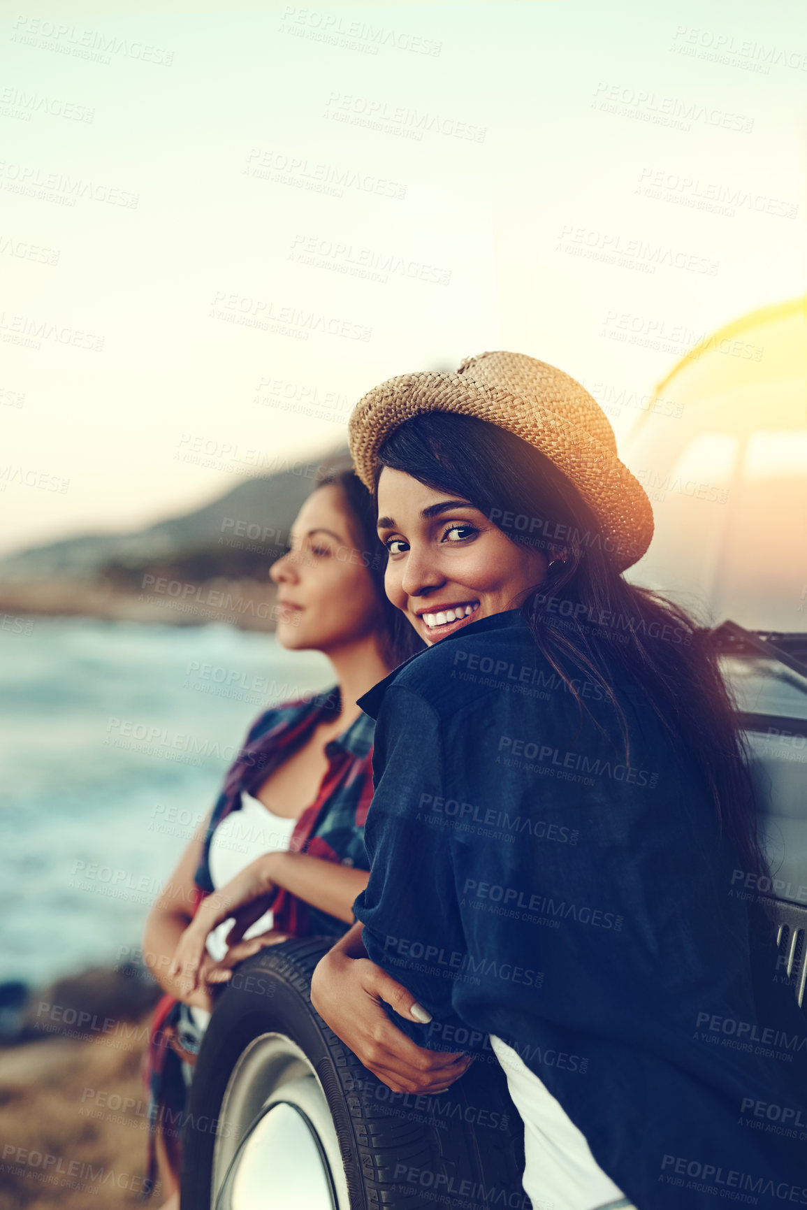 Buy stock photo Shot of two young friends stopping at the beach during their roadtrip