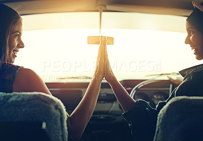 Buy stock photo Shot of two young friends giving each other a highfive on a road trip