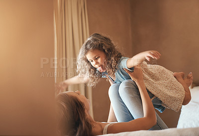 Buy stock photo Mom, girl and play with plane on bed, happy and bonding with flight, love and lifting in family home. Games, mother and daughter with tongue out, excited or emoji in morning at apartment in Australia