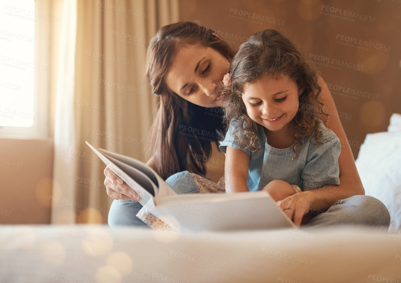 Buy stock photo Shot of a happy mother and daughter at home reading a storybook on the bed