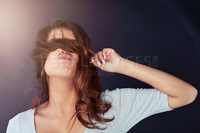 Buy stock photo Cropped shot of a beautiful young woman posing with her hair over her eyes in the studio