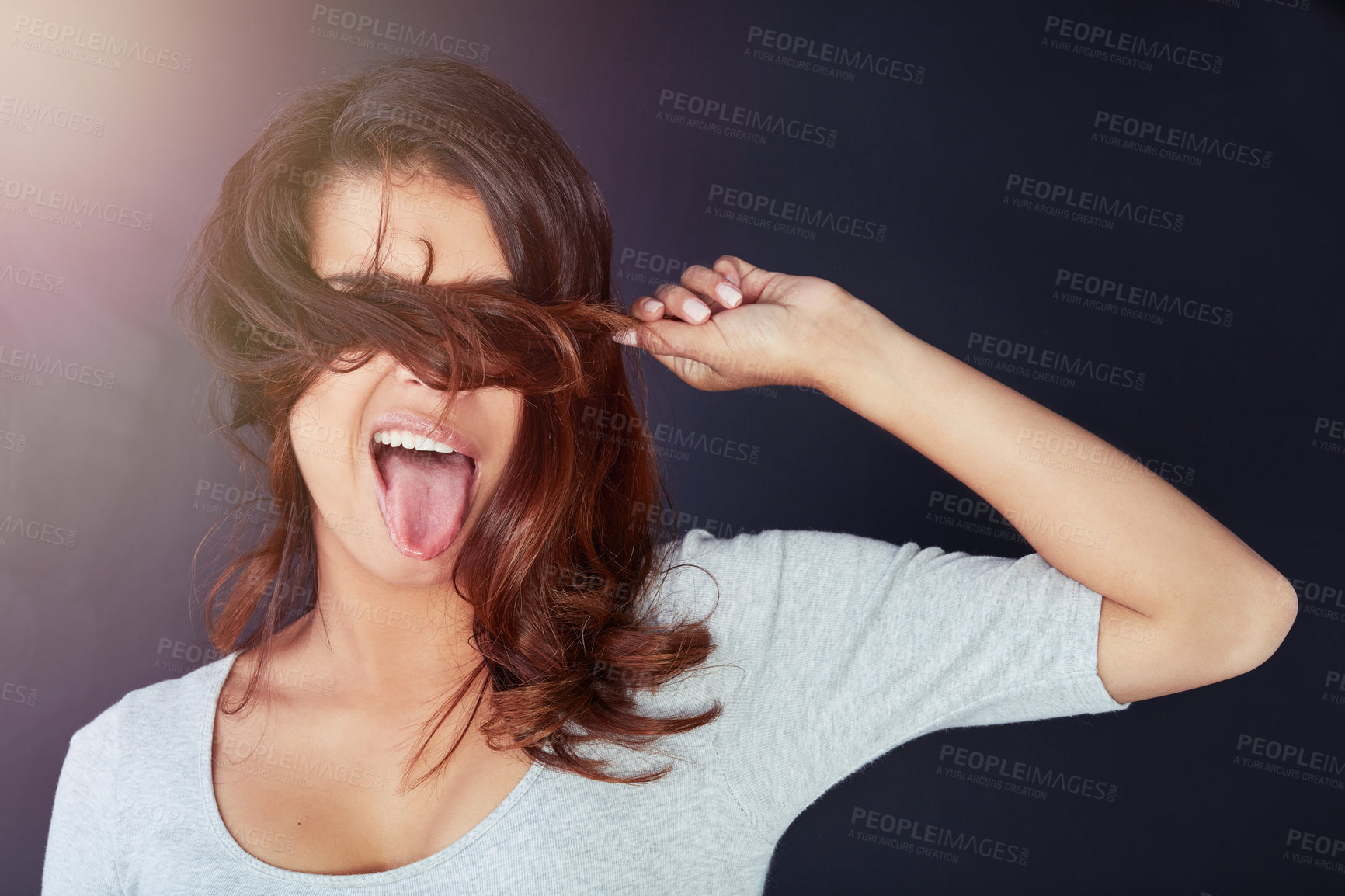 Buy stock photo Woman, hair and hiding on studio background for comic, joke and healthy growth or textures. Female person, tongue out and humor for haircare, keratin treatment and comedy or playful and funny girl