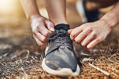 Buy stock photo Shot of a young person tying their shoelaces before going for a run outdoors