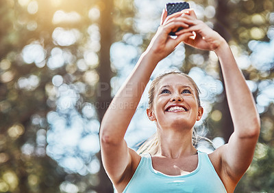Buy stock photo Shot of a young woman taking a photo of herself before her workout outdoors