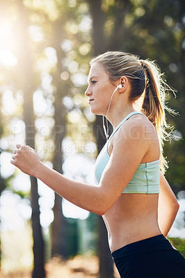 Buy stock photo Woman with earphones, running in forest and fitness with music, listening for motivation on run in park. Female runner outdoor, podcast or radio streaming for exercise and health, cardio and energy