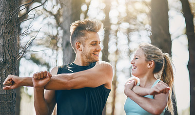 Buy stock photo Shot of a young couple looking at each other and stretching together outside in the forest