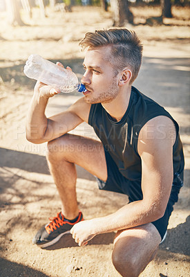 Buy stock photo Shot of a young man drinking water while out for a workout